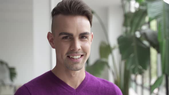 Portrait of Handsome Hispanic Gay Male Standing at Home Looking Happy to Camera with Smile alt