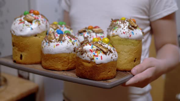 Child Holding Many Easter Cakes on a Tray Standing in the Kitchen alt