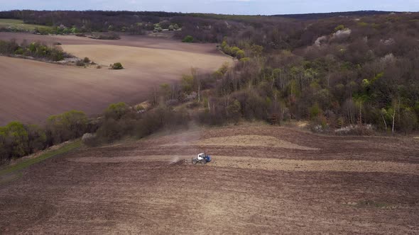 Aerial view large tractor cultivating a dry field. alt