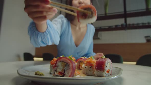 Beautiful Asian Female Enjoying Taste of Delicious Sushi Rolls alt