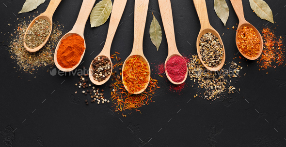 Various spices in wooden spoons on black background Stock Photo by  Prostock-studio