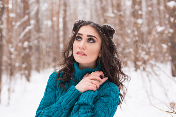 Portrait of young pretty woman walking in the winter snowy park