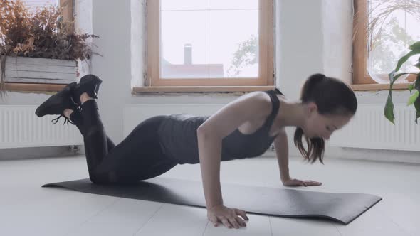 Young Fit Girl in Sportswear Does Pushups on Knees in Bright Room on Mat at Home alt