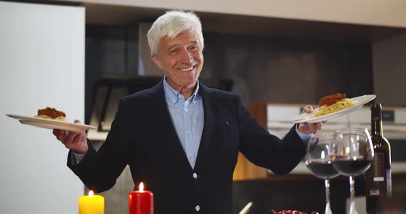 Portrait of Smiling Senior Man in Suit Holding Plates with Spaghetti Bolognese and Smiling at Camera alt
