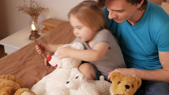 Little Girl Child Combs Soft Toys with Her Father Process of Education and Upbringing Home Bedroom