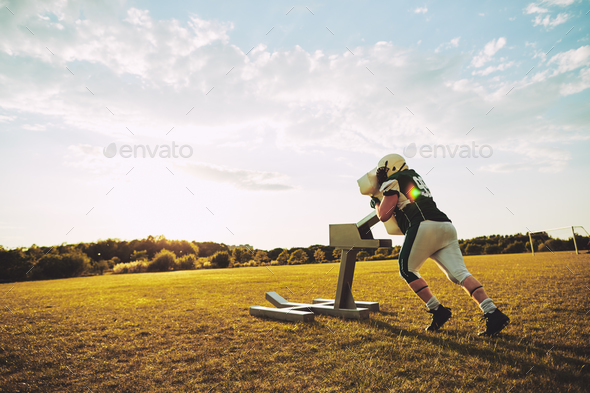 American football player doing tackling drills with a tackle sled