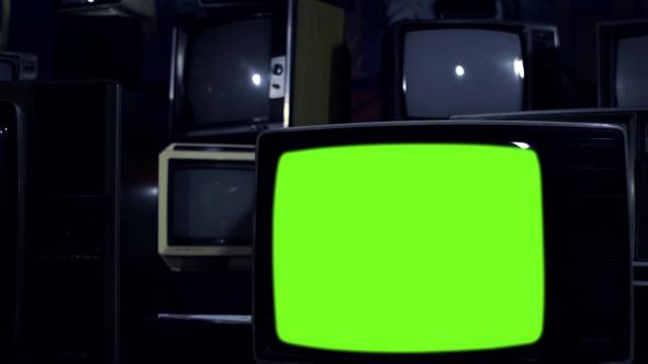 Retro TV Set Turning On Green Screen Among Many Vintage Televisions. Dolly Shot. alt
