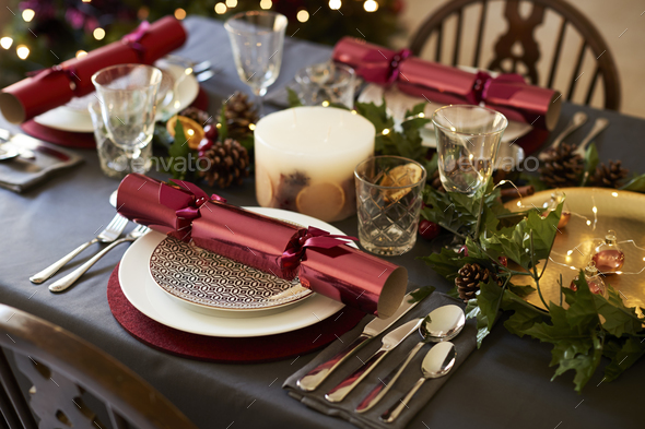 Close up of Christmas table setting with Christmas crackers arranged on plates - Stock Photo - Images