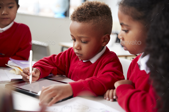 Three Kindergarten School Kids Sitting At Desk In A Classroom