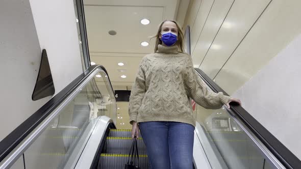 Woman in Medical Mask Getting Downstairs By Escalator in Trade Centre alt
