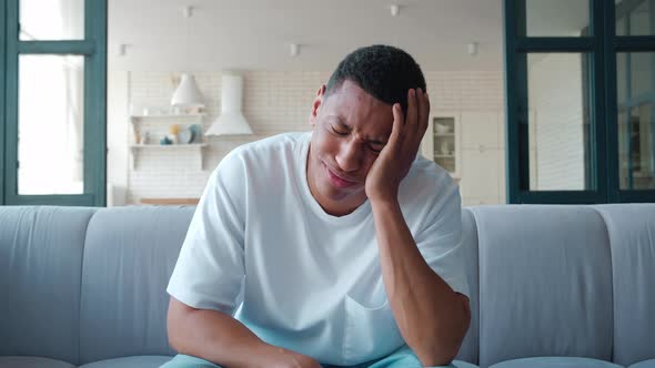 Depressed Young African American Guy Handsome Upset Mixed Race Man Sitting on Couch Looking at alt