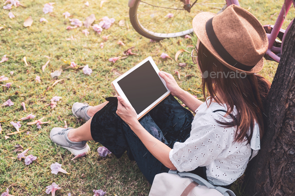 Young woman relaxing and using tablet and surf internet in the park - Stock Photo - Images