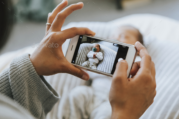 Mother snapping a photo of her newborn - Stock Photo - Images