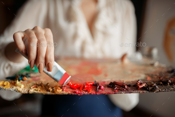 Female painter adds color to the palette in studio - Stock Photo - Images