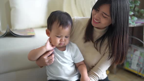 Young mother and little boy child reading book sitting on floor near sofa at home. Happy family.