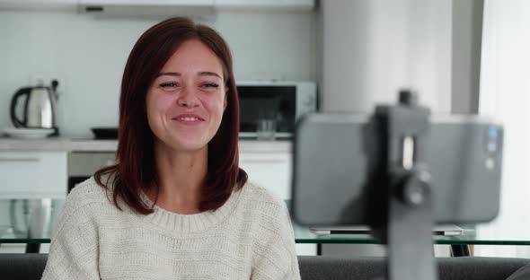 Woman Record Videovlog Using Smart Phone Seated on Couch Alone in Living Room Put Device on Tripod alt