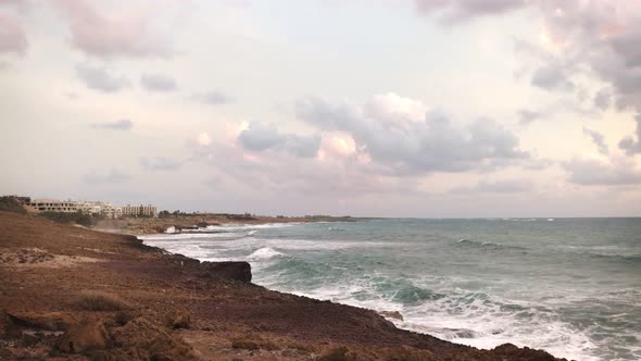View From the Shore of Large Sea Waves Crashing Against Rocks on a Cloudy Day alt
