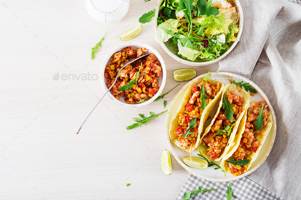 Mexican tacos with chicken meat, corn and tomato sauce.