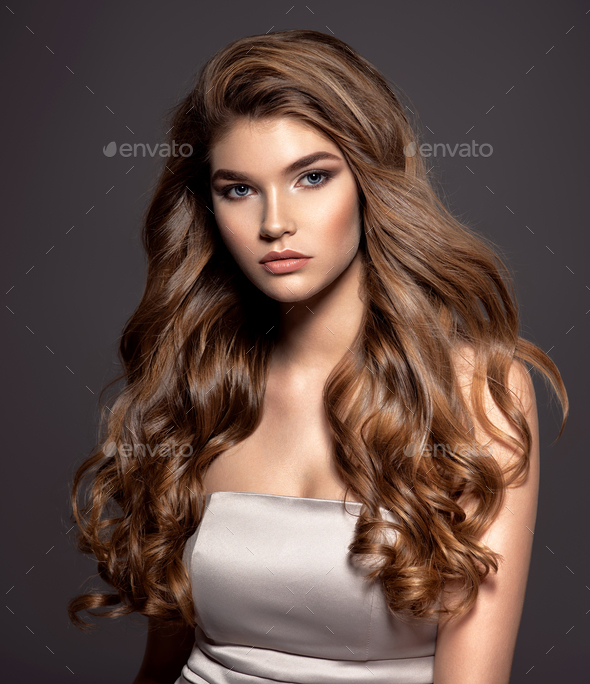 Young brown-haired woman with long curly hair. Stock Photo by valuavitaly