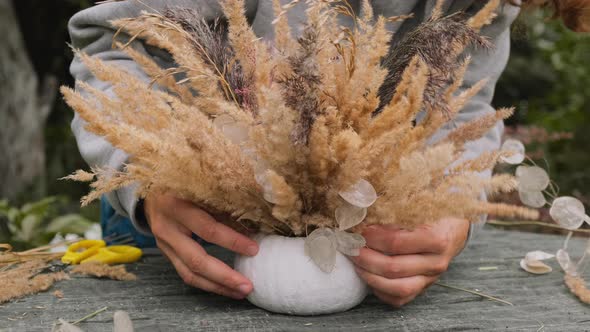 Florist Makes Thanksgiving Day Flower Arrangement in White Painted Pumpkin Flowerpot alt
