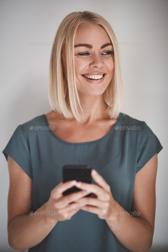 Female entrepreneur smiling while reading texts against a gray background - Stock Photo - Images