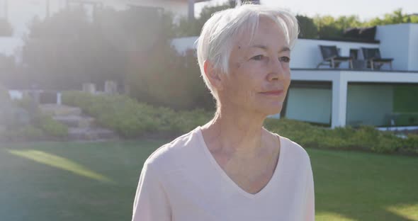 Portrait of happy senior caucasian woman in garden on sunny day at retirement home alt