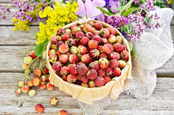 Strawberries in box with flowers on old board