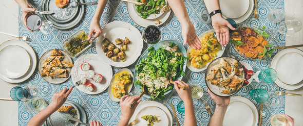 Flat-lay of hands holding mediterranean starters and drinks, wide composition - Stock Photo - Images