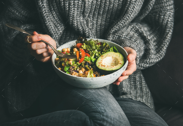 Woman in sweater eating fresh salad, avocado, beans and vegetables - Stock Photo - Images