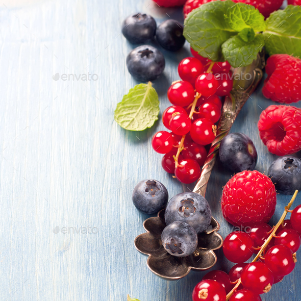 Berries and vintage spoon on a blue background - Stock Photo - Images