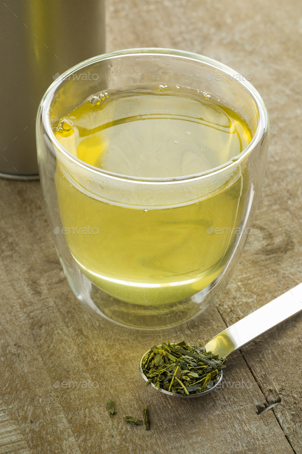 Cup of Japanese green tea and a spoon with dried green tea leave