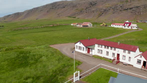 Drone View Orbit Around Iceland Flag Waving Out of Typical Building in Iceland Highland alt