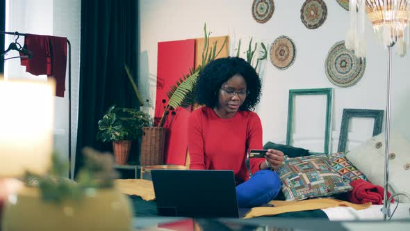 Young African Lady Is Doing an Online Purchase in Self-quarantine alt