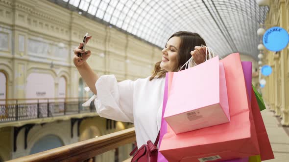 Pretty Plussized Woman Makes Selfie Holding Shopping Bags