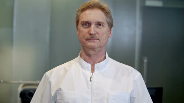 Portrait of a Confident Senior Doctor Standing at Hospital While Looking at Camera alt