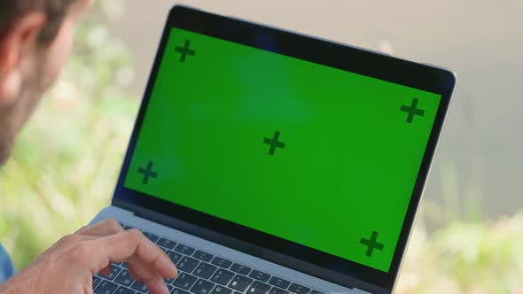 Male Freelance Working at a Laptop While Sitting Near Camping Typing Text and Remote Work in Nature alt