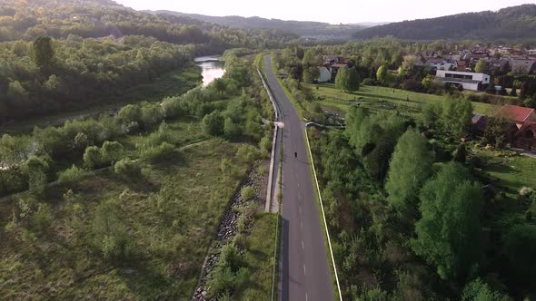 Boy roller skating on the lonely sunset road (drone shot) alt