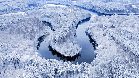Winter winding river and snowy forest. Aerial view of Poland alt
