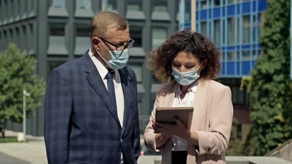 Boss and Secretary in Medical Masks Having Consultation Outdoor alt