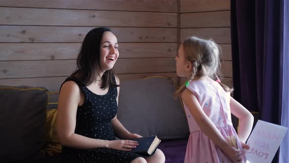 Little Girl Greeting Mom with Mothers Day Indoors alt