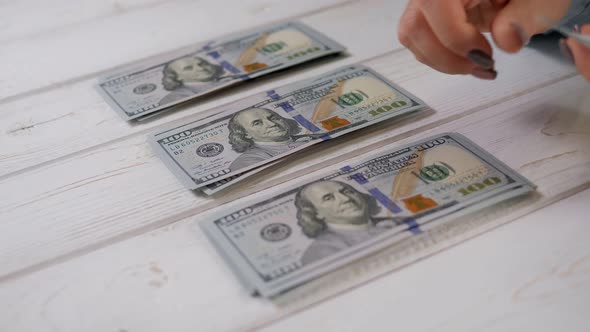 A Business Lady Counts Hundreddollar Bills and Puts Them in Three Piles alt