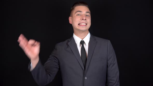 Young Businessman Shows Ok Sign on His Hand. Man in a Black Suit on a Black Background