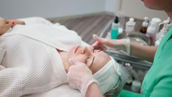 Female Beautician Makes Face Rejuvenation and Cleansing Procedure for Girl alt