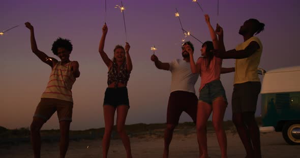 Young adult friends having fun on the beach at night with sparklers 4k alt