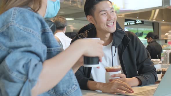 Happy asian couple take off face mask in a coffee shop surfing internet on laptop. alt