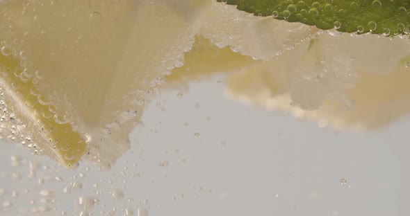 Slow Motion Macro Shot of a Lemon Slice in Water Bubbles Drinking Cold Lemonade alt
