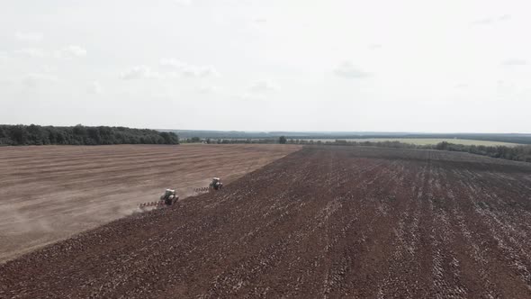 Agricultural machinery plowing fields after harvesting. Tractors working on fields. alt