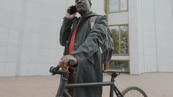 Black Man Standing with Bike and Talking on Phone alt