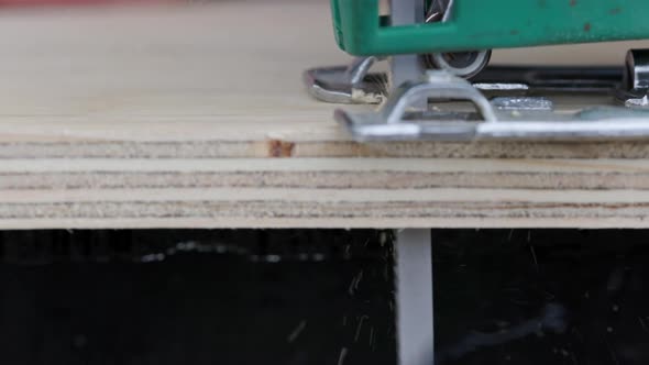 Sawdust Flies Off a Metal Blade As the Jigsaw Cuts Into a Sheet Plywood Workpiece alt