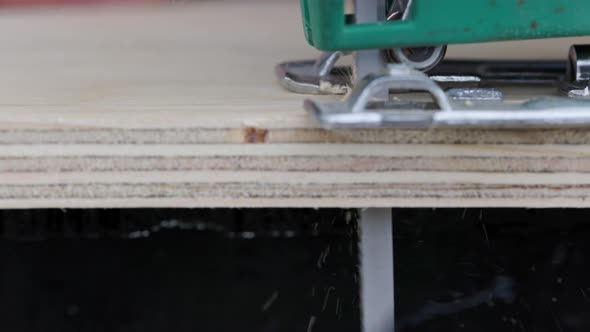Sawdust Flies Off a Metal Blade As the Jigsaw Cuts Into a Sheet Plywood Workpiece